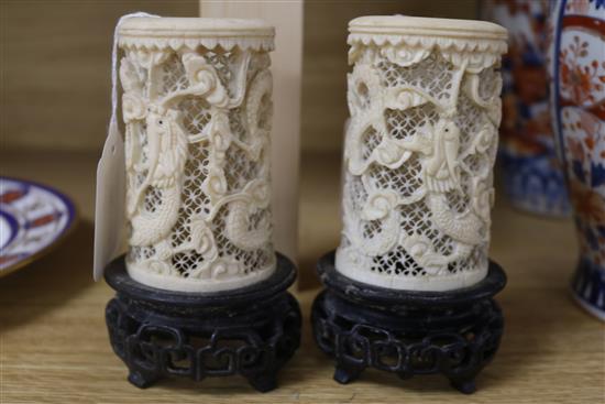 A pair of Chinese carved ivory tusk reticulated vases, carved with dragons among clouds and with carved and pierced hardwood stands